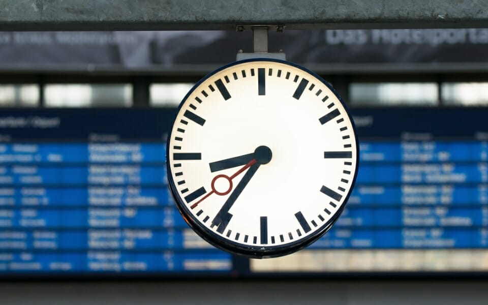 train station clock during off-peak time with departures board in the background