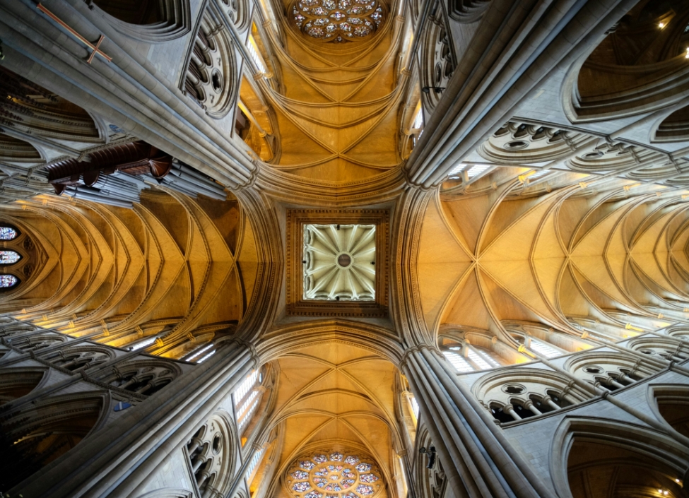A view of the ceiling of Truro Cathedral made of granite with stained glass windows.